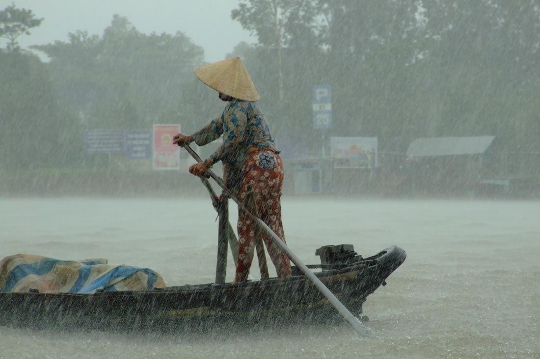 barquero remando en el río Mekong (Vietnam) durante una lluvia torrencial propia de la época del monzón