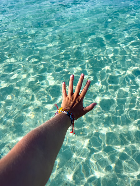 La mano de Inma sobre las turquesas y cristalinas agua de Rasdhoo
