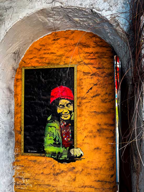 Pintura de street art de una mujer asomada a una ventana