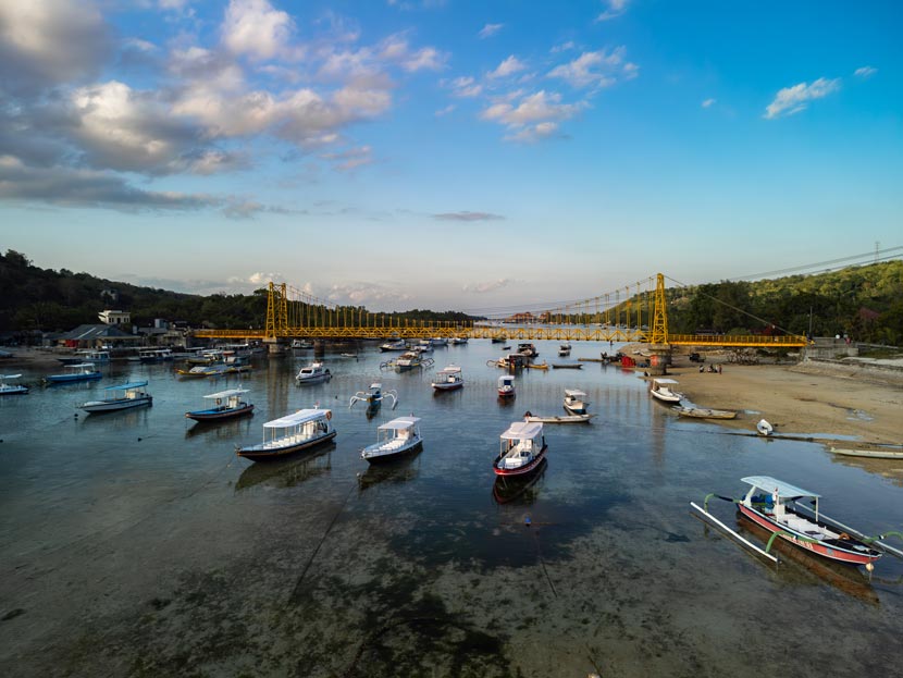 El Yellow Bridge al atardecer con el mar repletoo de barcas, una estampa que ver en Nusa Ceningan