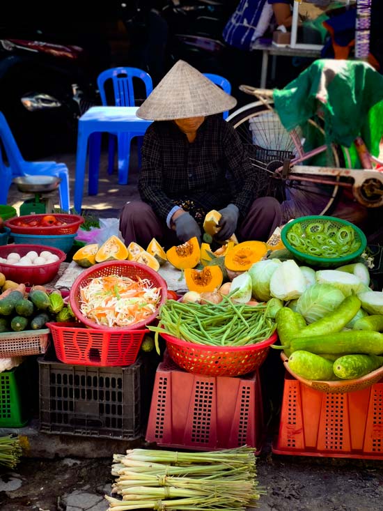 Señora preparando fruta para vender en el mercado local de Hoi An, una de las cosas más auténticas que ver en Hoi An