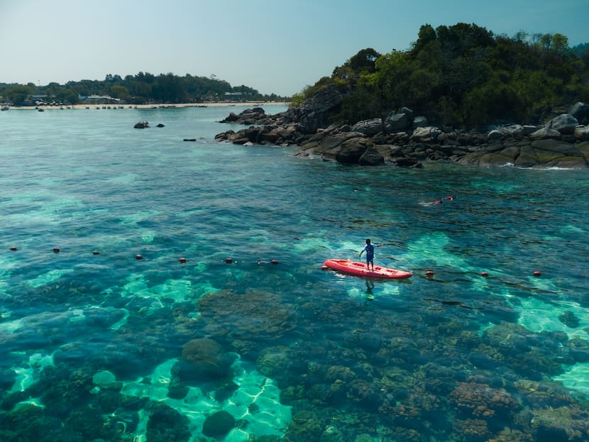 Niño pescando encima de un kayak en Koh Kra, Koh Lipe